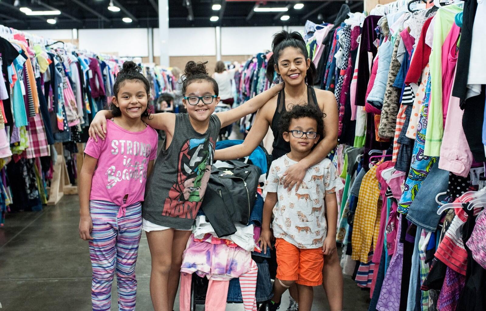 A mom and her two kids stand in the shoe section for a happy family photo.